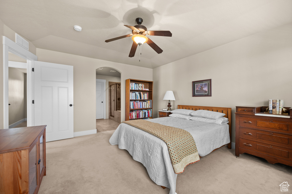 Bedroom with light colored carpet, arched walkways, baseboards, and a ceiling fan
