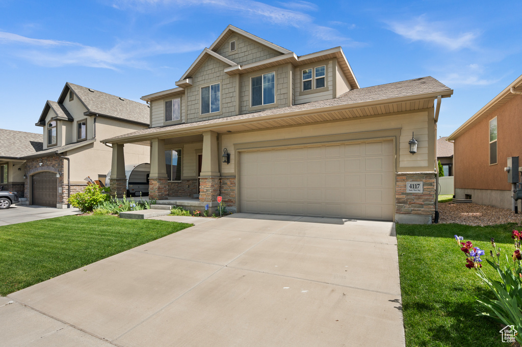 Craftsman inspired home featuring stone siding, a front lawn, concrete driveway, and covered porch