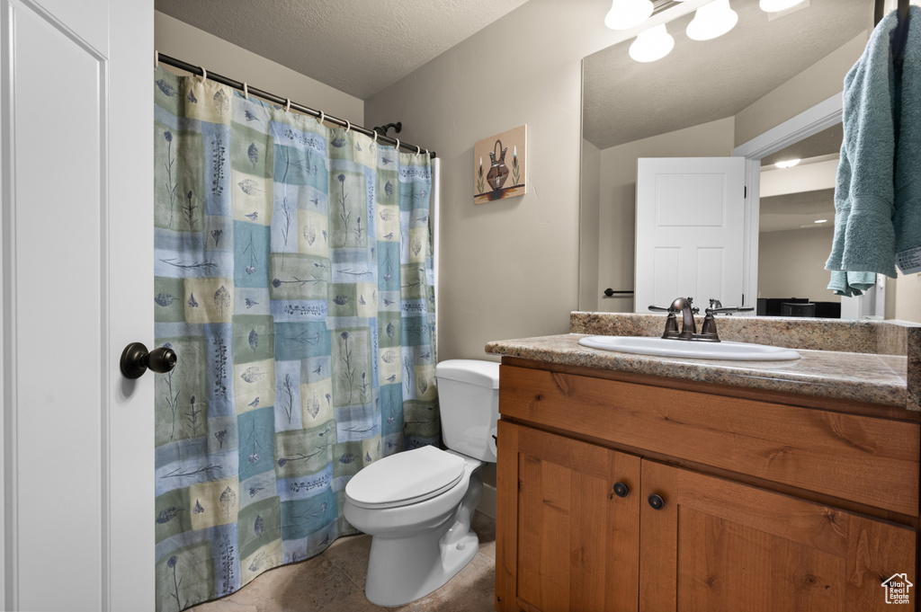 Full bath with toilet, vanity, and a textured ceiling