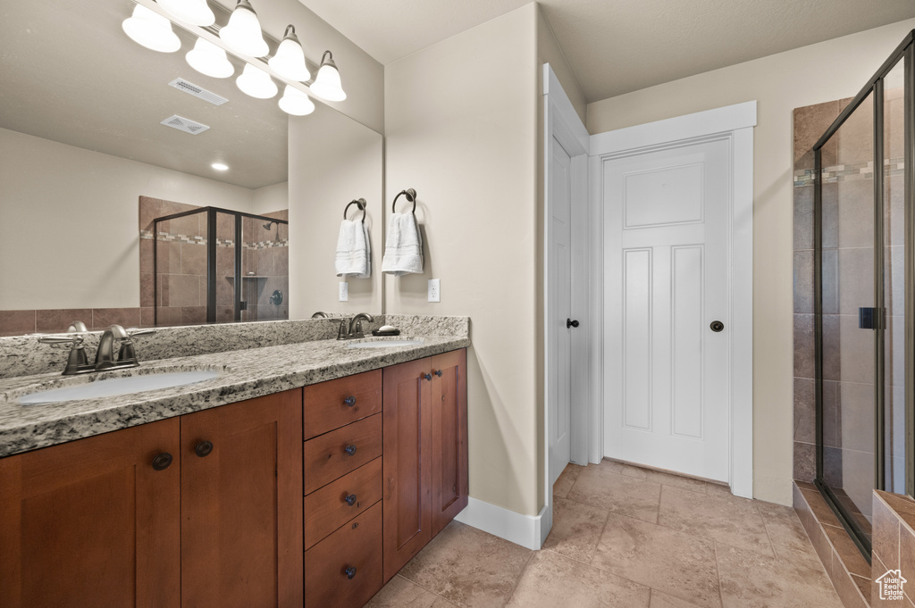 Full bath featuring a stall shower, double vanity, and baseboards