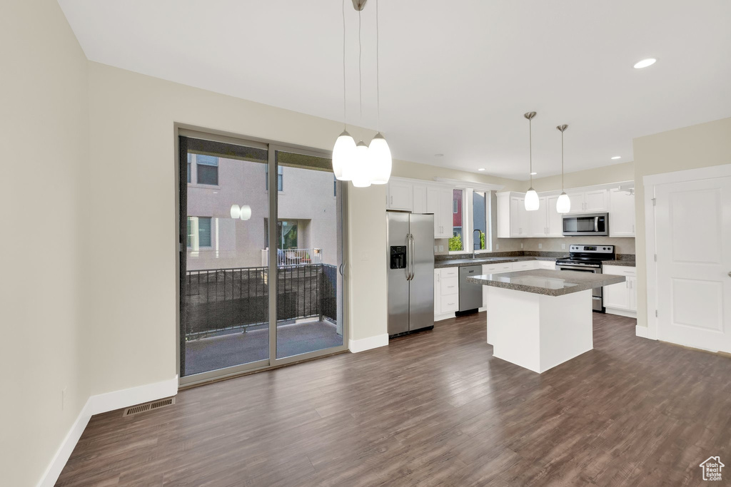 Kitchen with appliances with stainless steel finishes, white cabinets, a kitchen island, dark wood finished floors, and recessed lighting