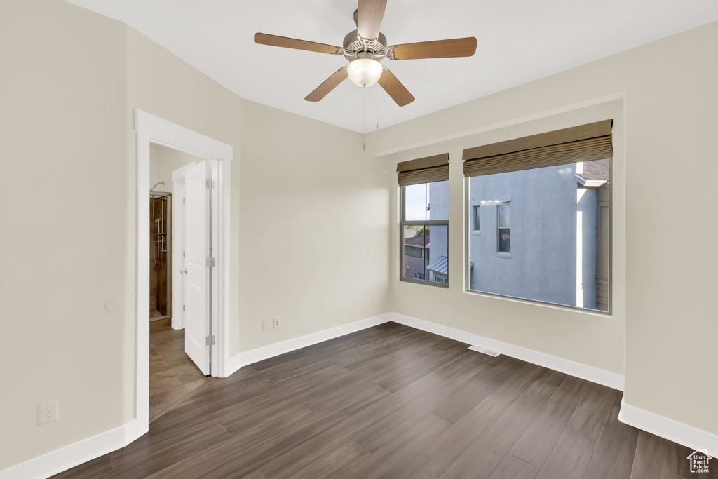 Empty room with ceiling fan, dark wood-style floors, and baseboards