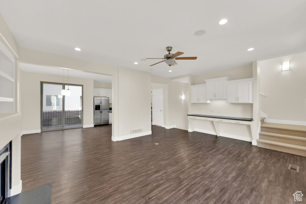 Unfurnished living room featuring dark wood finished floors, ceiling fan, recessed lighting, baseboards, and stairs