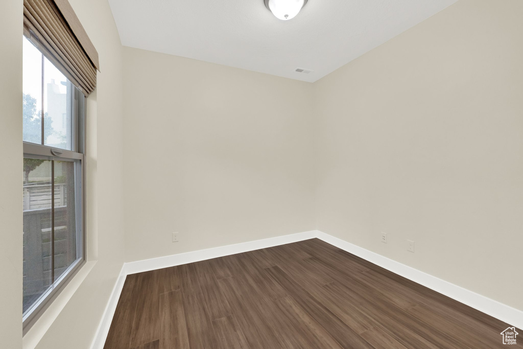Empty room featuring dark wood-style flooring and baseboards