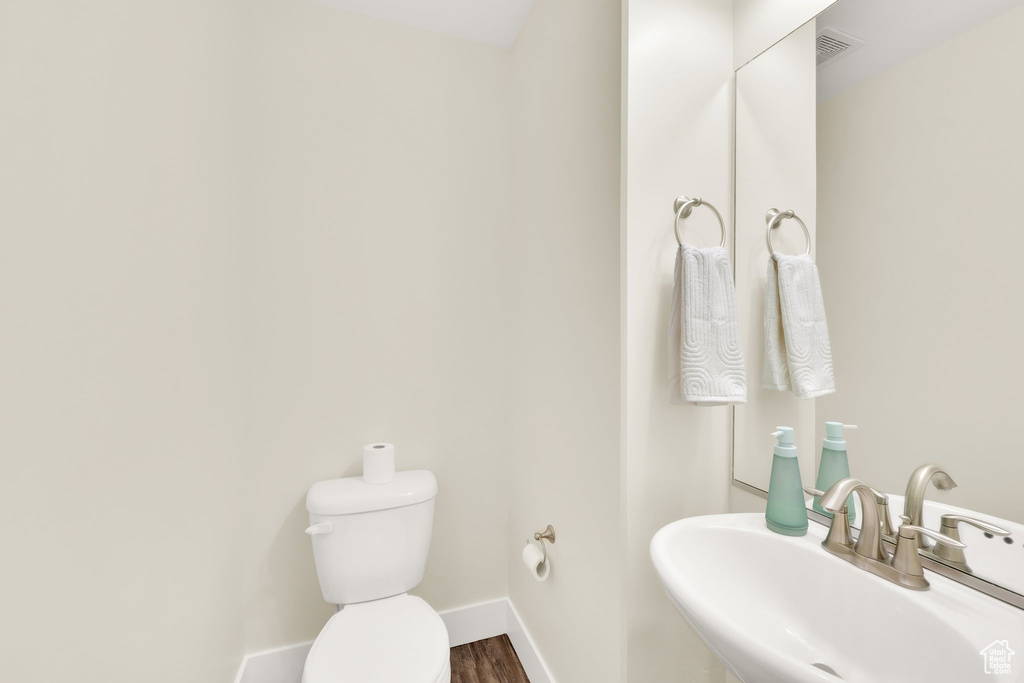 Bathroom with a sink, toilet, baseboards, and wood finished floors