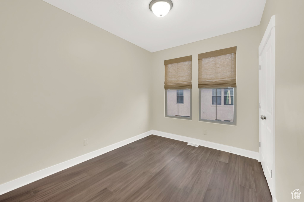 Spare room featuring baseboards and dark wood finished floors