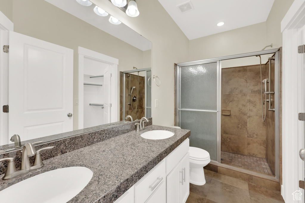 Bathroom featuring a stall shower, double vanity, toilet, and tile patterned floors