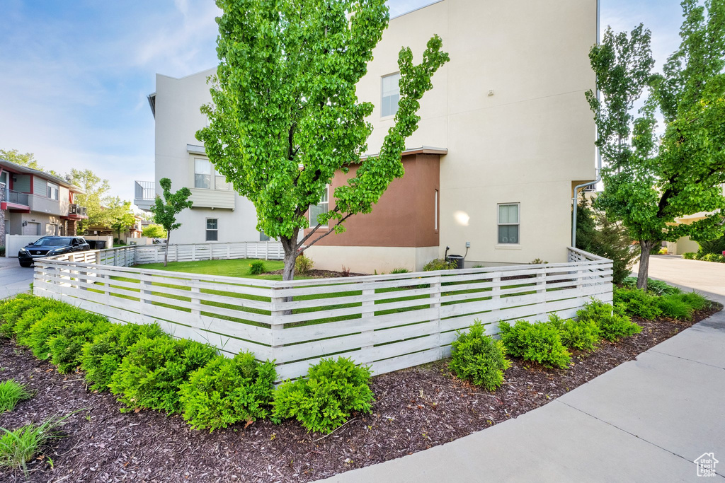 View of side of property featuring stucco siding and a fenced front yard