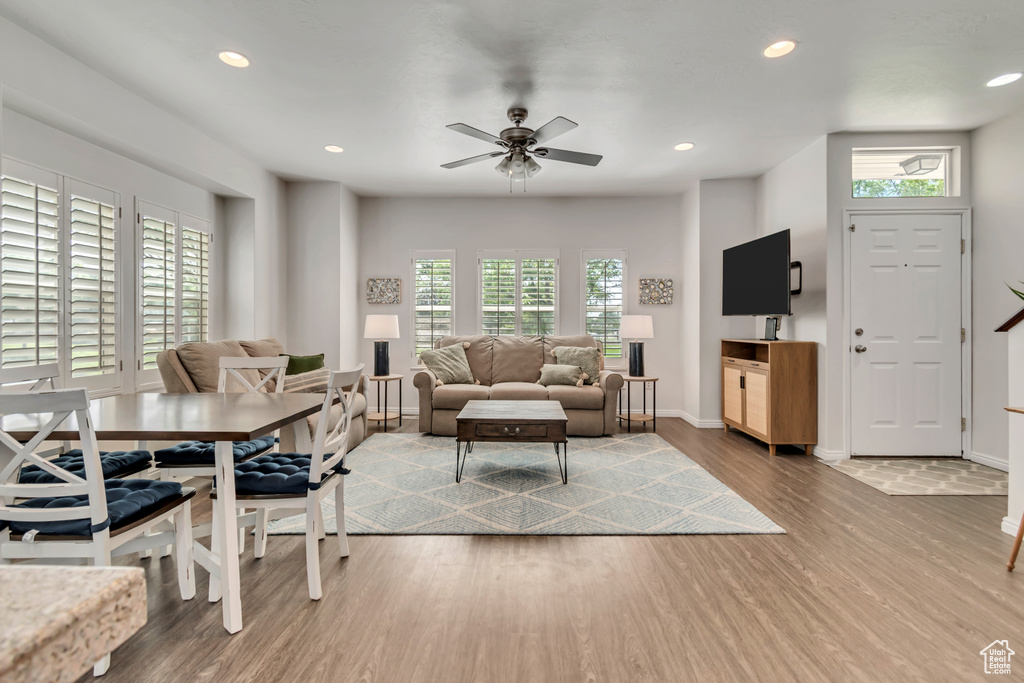 Living area with wood finished floors, healthy amount of natural light, ceiling fan, baseboards, and recessed lighting