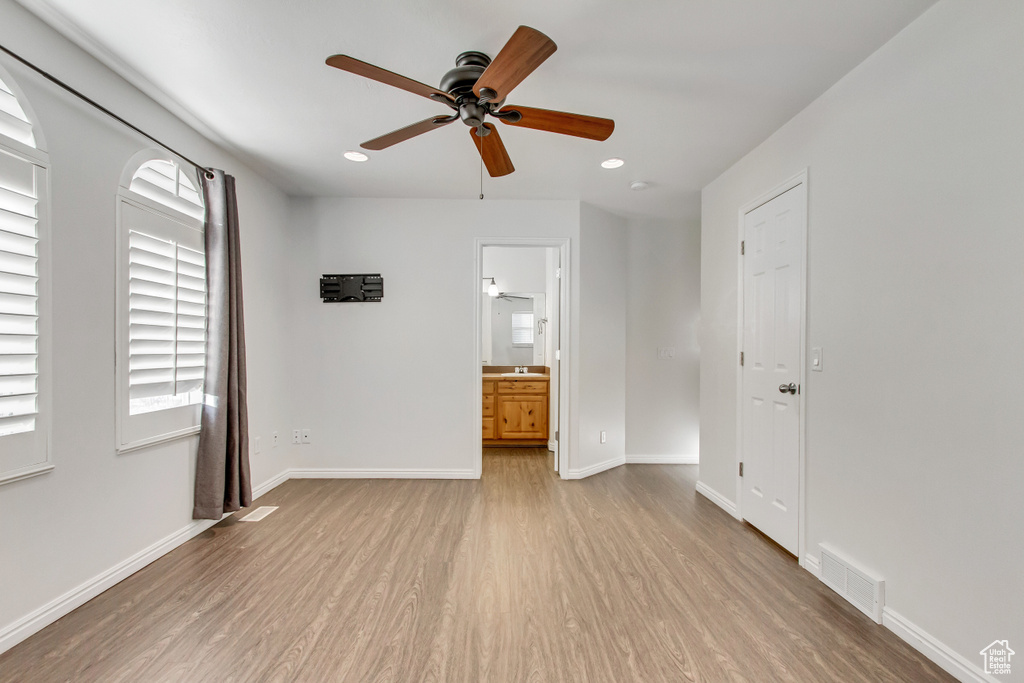 Spare room featuring light wood-style flooring, a ceiling fan, baseboards, and recessed lighting