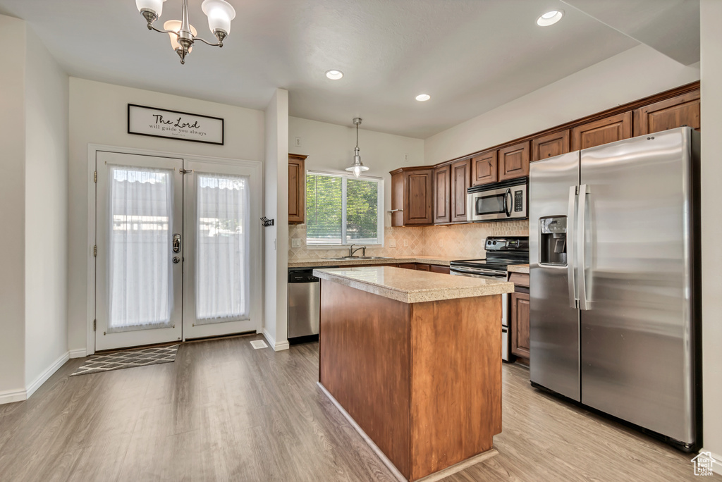 Kitchen featuring appliances with stainless steel finishes, light wood-type flooring, decorative backsplash, a center island, and recessed lighting