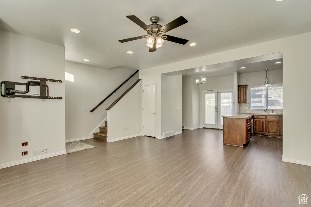 Unfurnished living room with dark wood-style floors, a sink, ceiling fan, recessed lighting, and stairs
