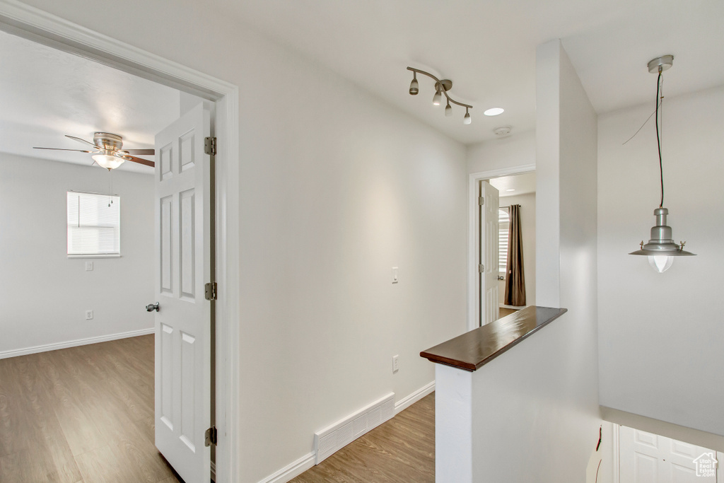 Corridor with light wood-type flooring and baseboards