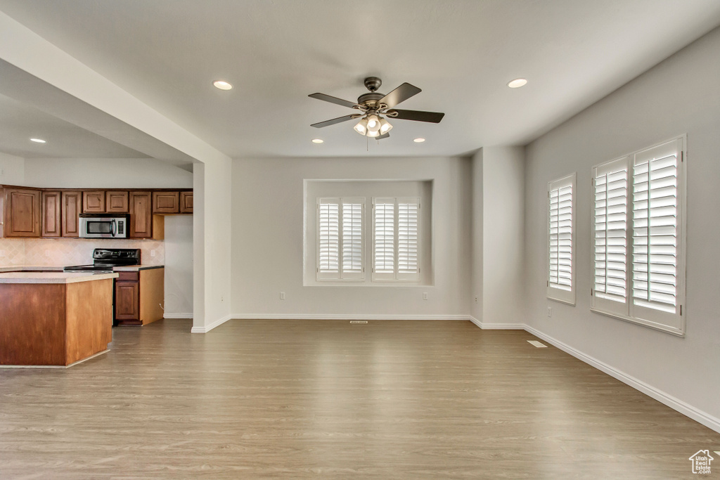 Kitchen featuring stainless steel microwave, black range with electric stovetop, healthy amount of natural light, wood finished floors, and recessed lighting
