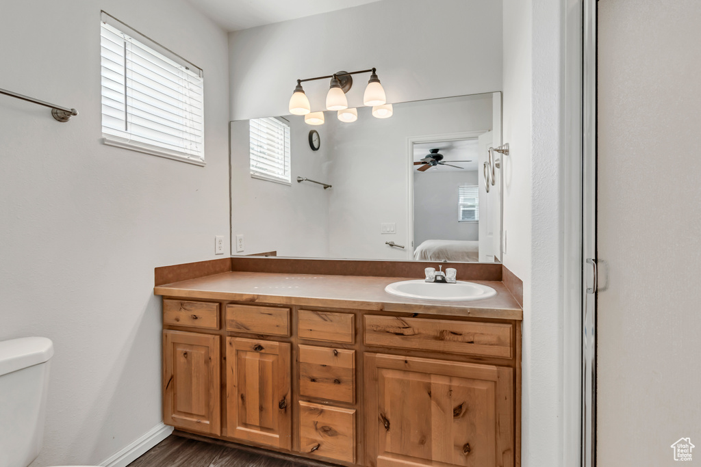 Full bath with toilet, vanity, ensuite bath, a ceiling fan, and wood finished floors