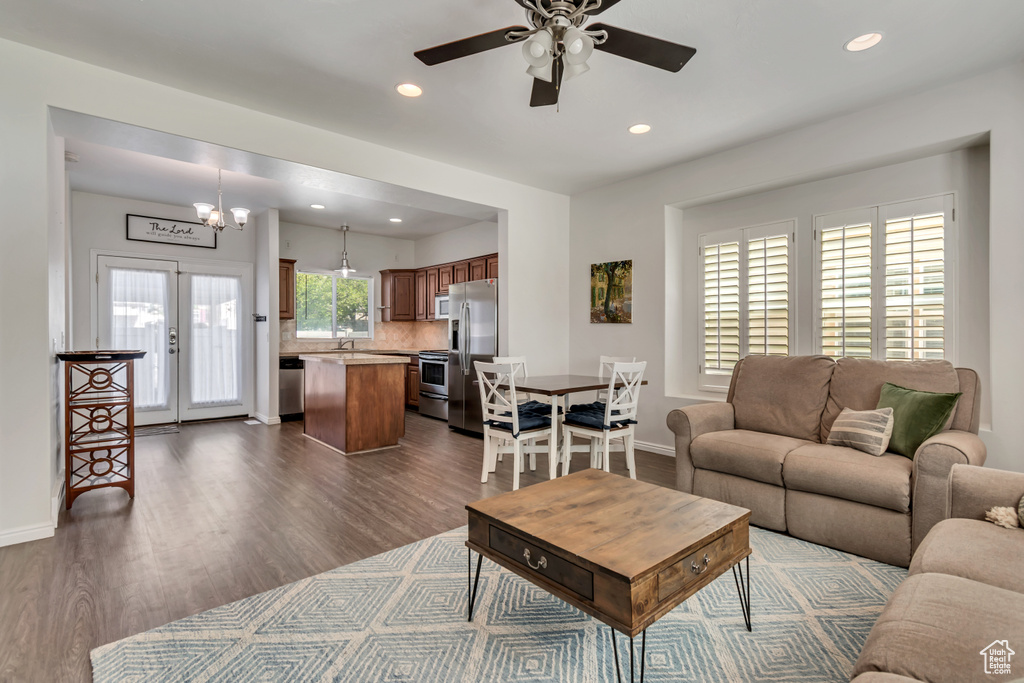 Living room with dark wood-type flooring, ceiling fan, recessed lighting, baseboards, and a chandelier