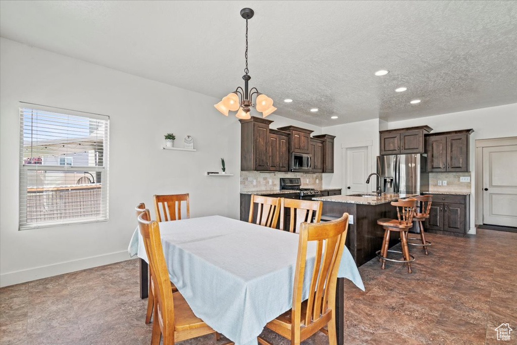 Dining area featuring a chandelier, recessed lighting, a textured ceiling, and baseboards