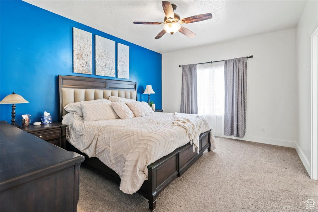 Bedroom with light colored carpet, baseboards, ceiling fan, and a textured ceiling