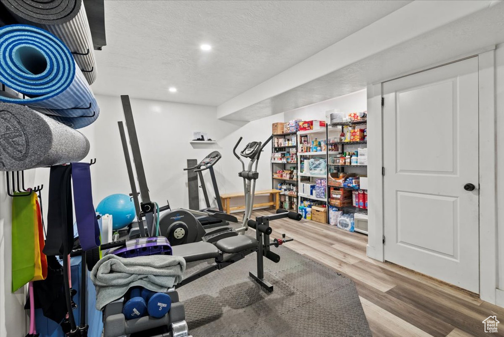 Exercise room with wood finished floors, recessed lighting, and a textured ceiling