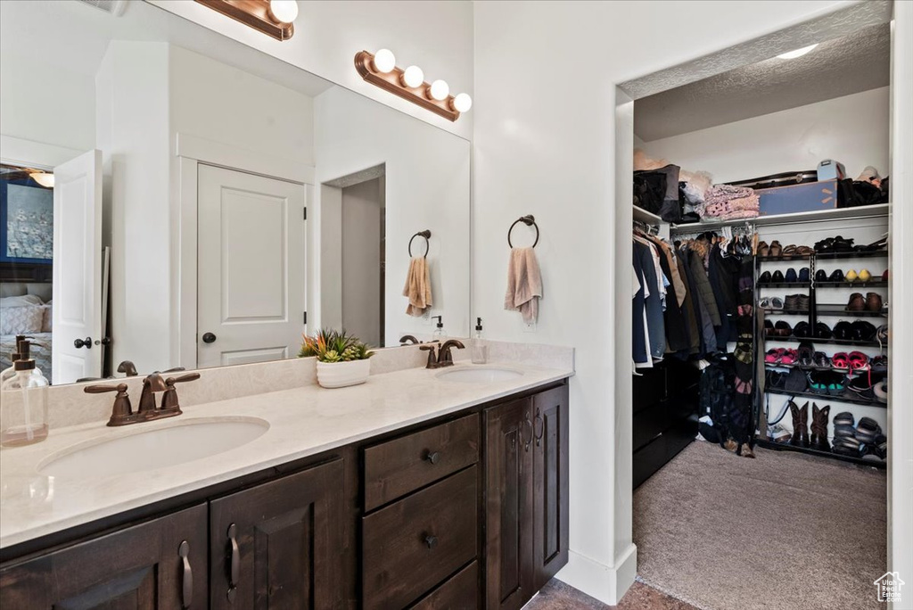 Bathroom featuring double vanity, a walk in closet, and ensuite bathroom