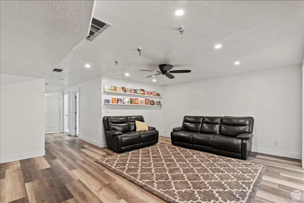 Living area featuring recessed lighting, a textured ceiling, a ceiling fan, wood finished floors, and baseboards