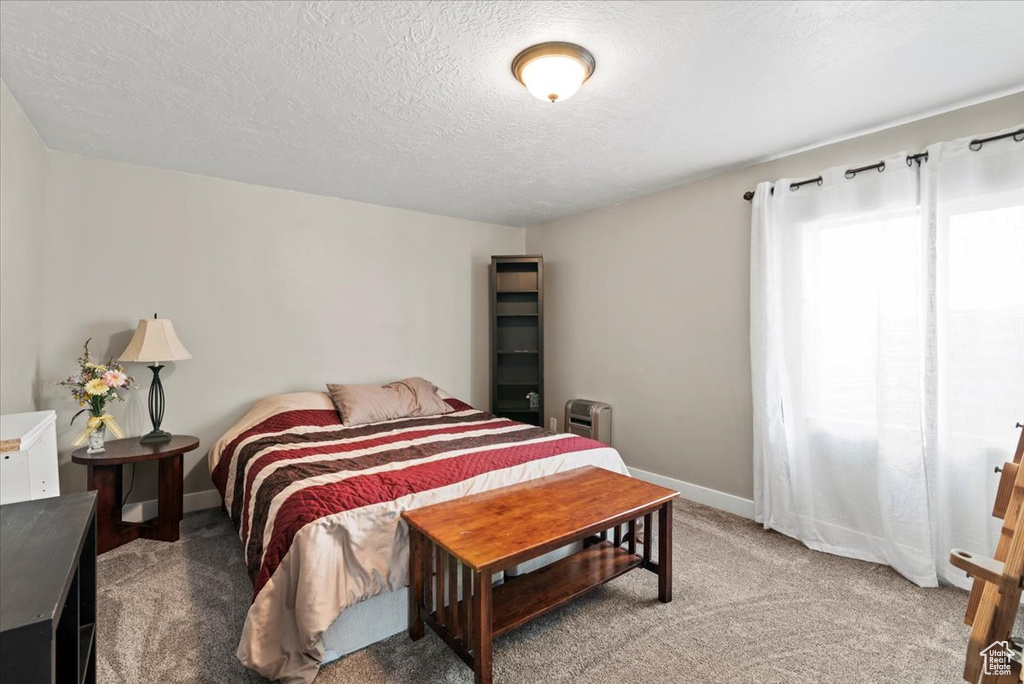 Bedroom with light colored carpet, a textured ceiling, and baseboards