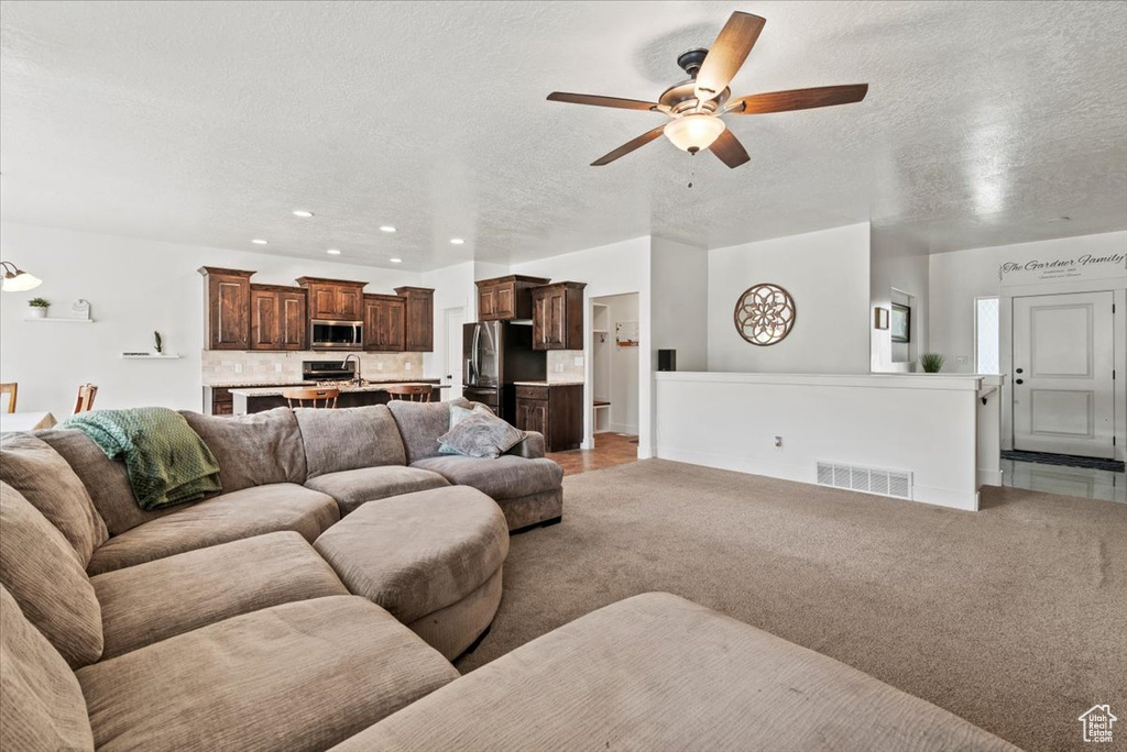 Living area featuring a textured ceiling, a ceiling fan, recessed lighting, and light carpet