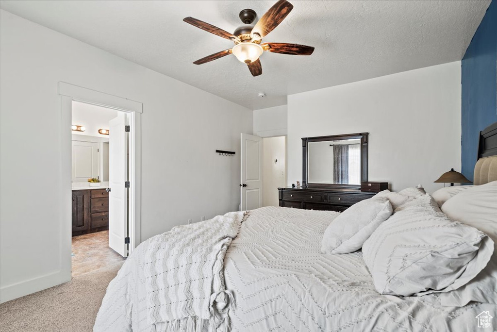 Bedroom featuring light carpet, baseboards, ensuite bath, and ceiling fan