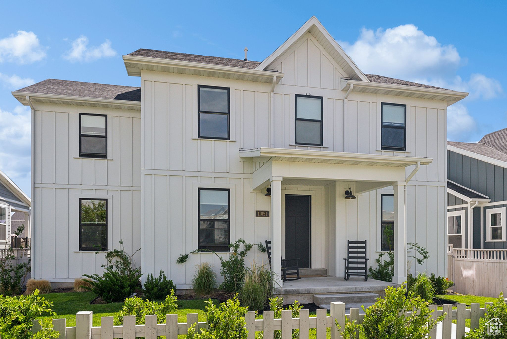Modern farmhouse with board and batten siding, covered porch, and a shingled roof
