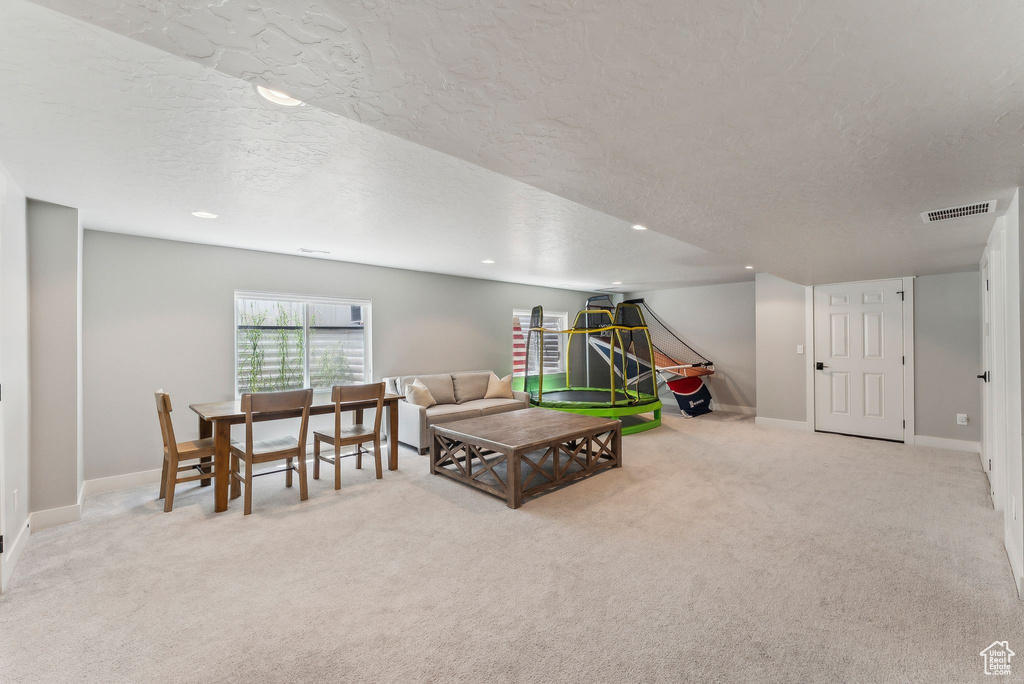 Living area featuring a textured ceiling, carpet flooring, recessed lighting, and baseboards