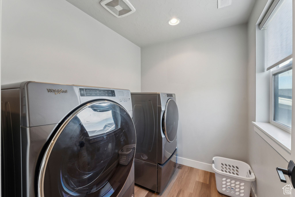 Washroom featuring washing machine and clothes dryer, light wood-style flooring, baseboards, and recessed lighting