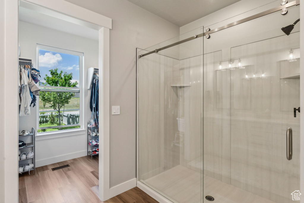 Full bath featuring a stall shower, wood finished floors, and baseboards