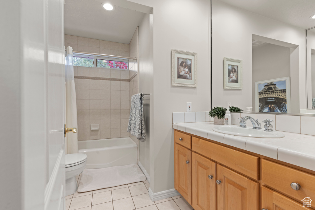 Full bath with tile patterned flooring, vanity, shower / tub combo with curtain, toilet, and baseboards