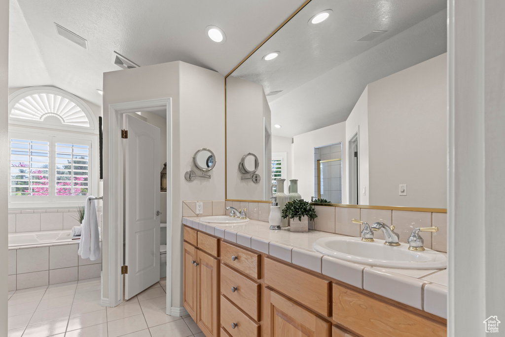 Full bath featuring tile patterned floors, double vanity, a garden tub, toilet, and an enclosed shower