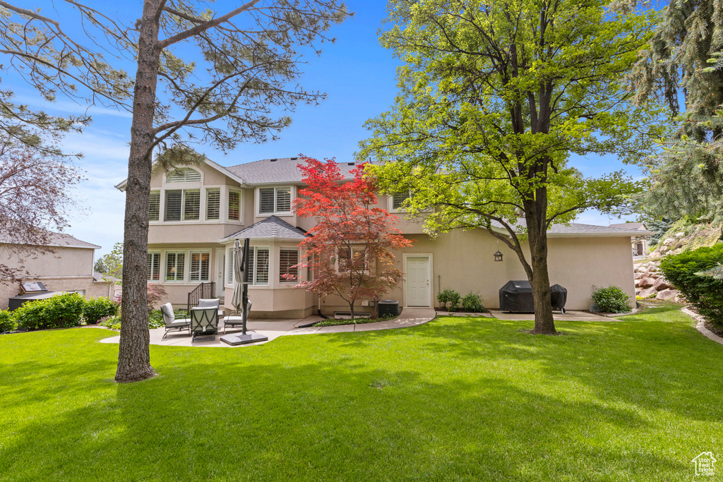 Back of house featuring a patio, stucco siding, and a yard