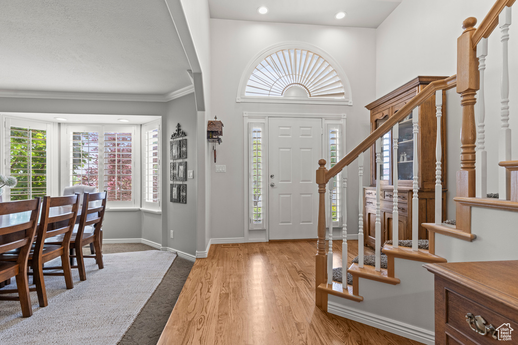 Foyer entrance featuring stairway, baseboards, wood finished floors, ornamental molding, and recessed lighting