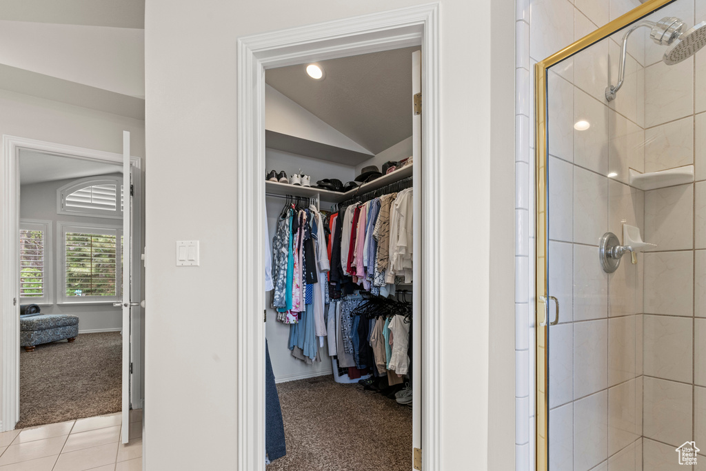 Spacious closet with vaulted ceiling and light colored carpet