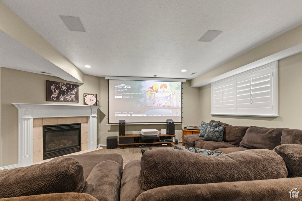 Carpeted living area featuring a tiled fireplace, recessed lighting, and baseboards