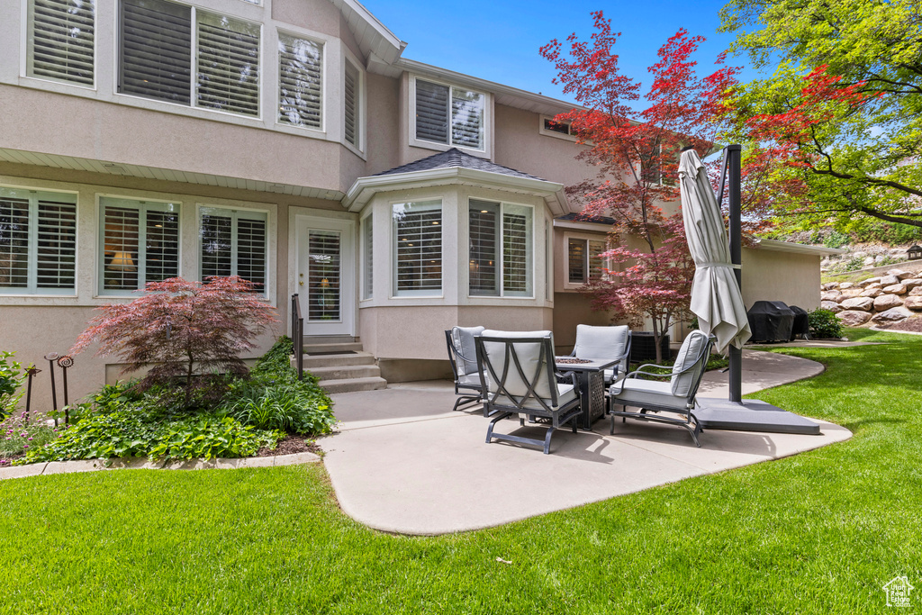 Rear view of property with stucco siding, entry steps, a patio, and a yard