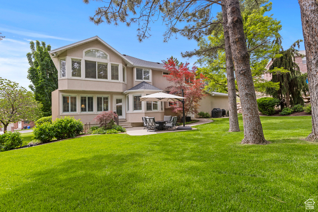 Back of property with stucco siding, entry steps, and a lawn
