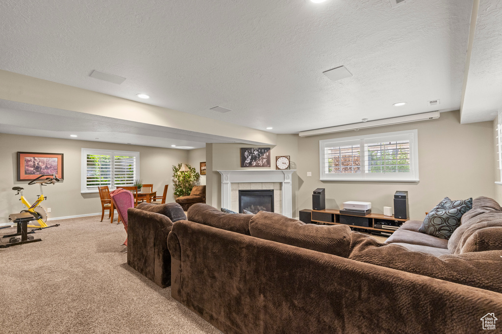 Living area with light colored carpet, a tile fireplace, recessed lighting, a textured ceiling, and baseboards