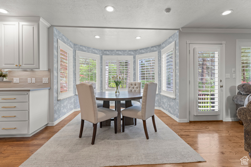 Dining space with crown molding, baseboards, a textured ceiling, recessed lighting, and wood finished floors