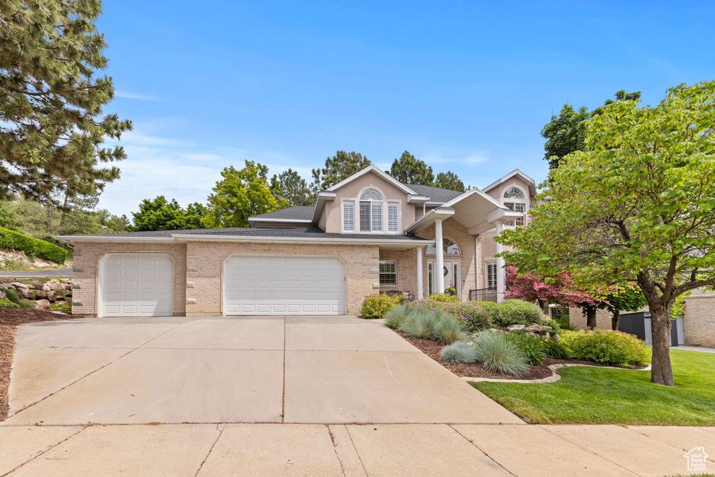 View of front facade with a garage, driveway, a front yard, and brick siding