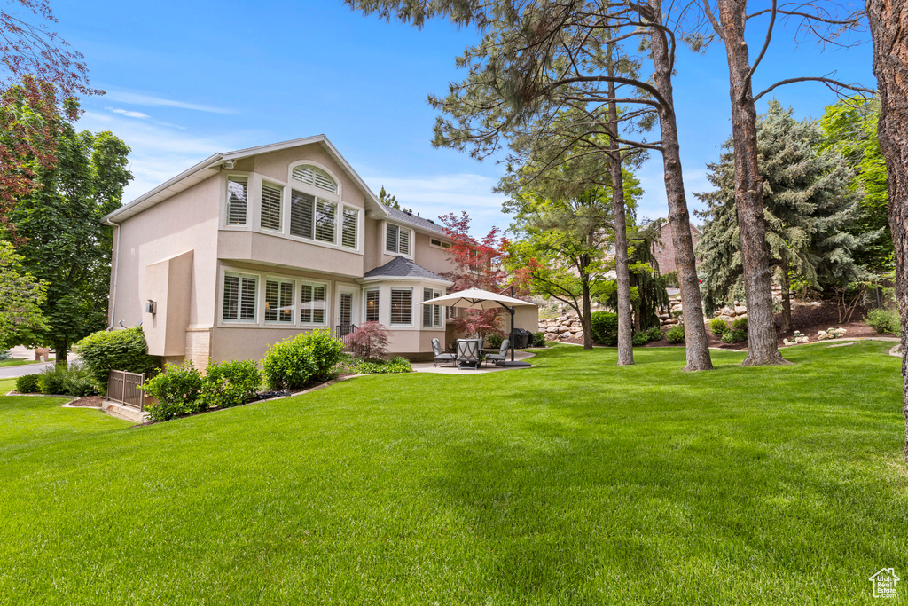 Rear view of property featuring stucco siding, a yard, and a patio