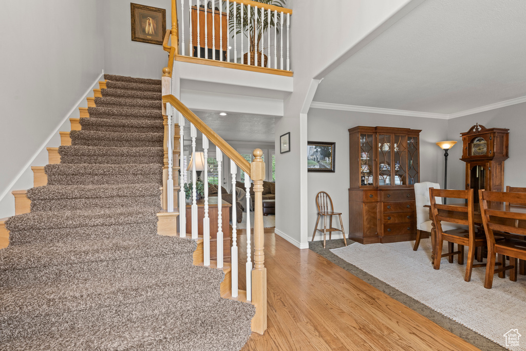 Staircase with wood finished floors, crown molding, and baseboards