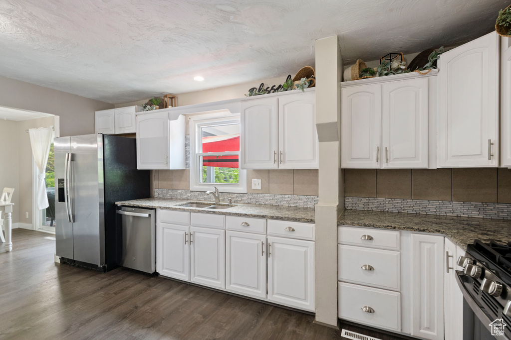 Kitchen featuring appliances with stainless steel finishes, a sink, white cabinetry, tasteful backsplash, and recessed lighting