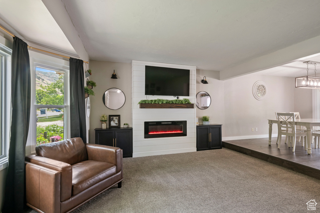 Living area featuring carpet, a large fireplace, and baseboards