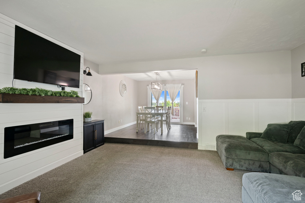 Living area with carpet flooring, a glass covered fireplace, a decorative wall, and wainscoting