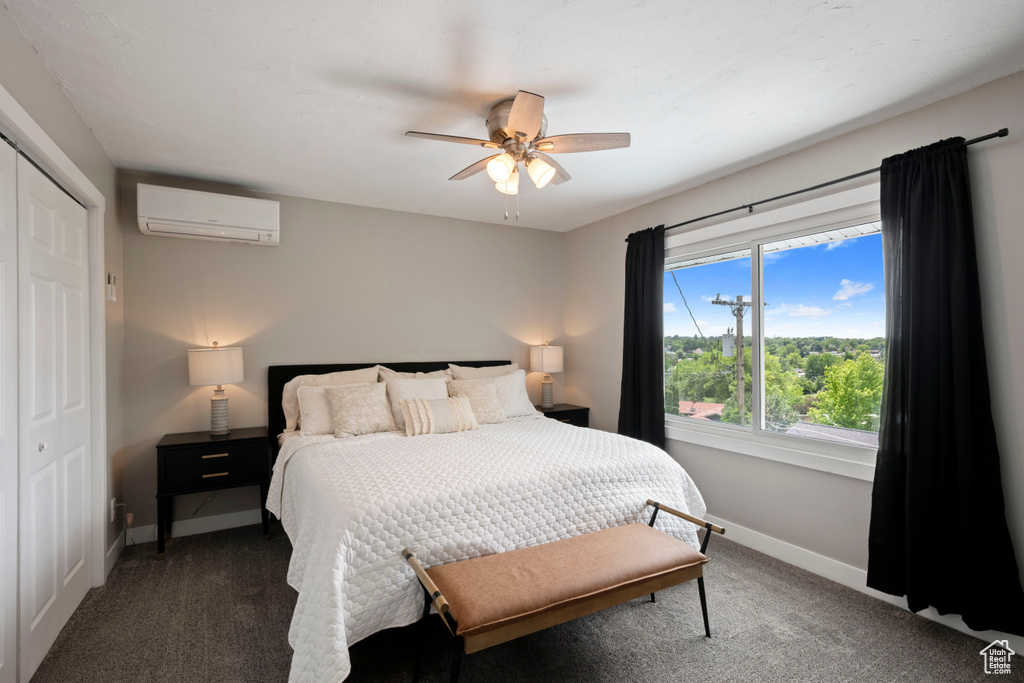 Carpeted bedroom featuring a wall mounted air conditioner, baseboards, a closet, and ceiling fan