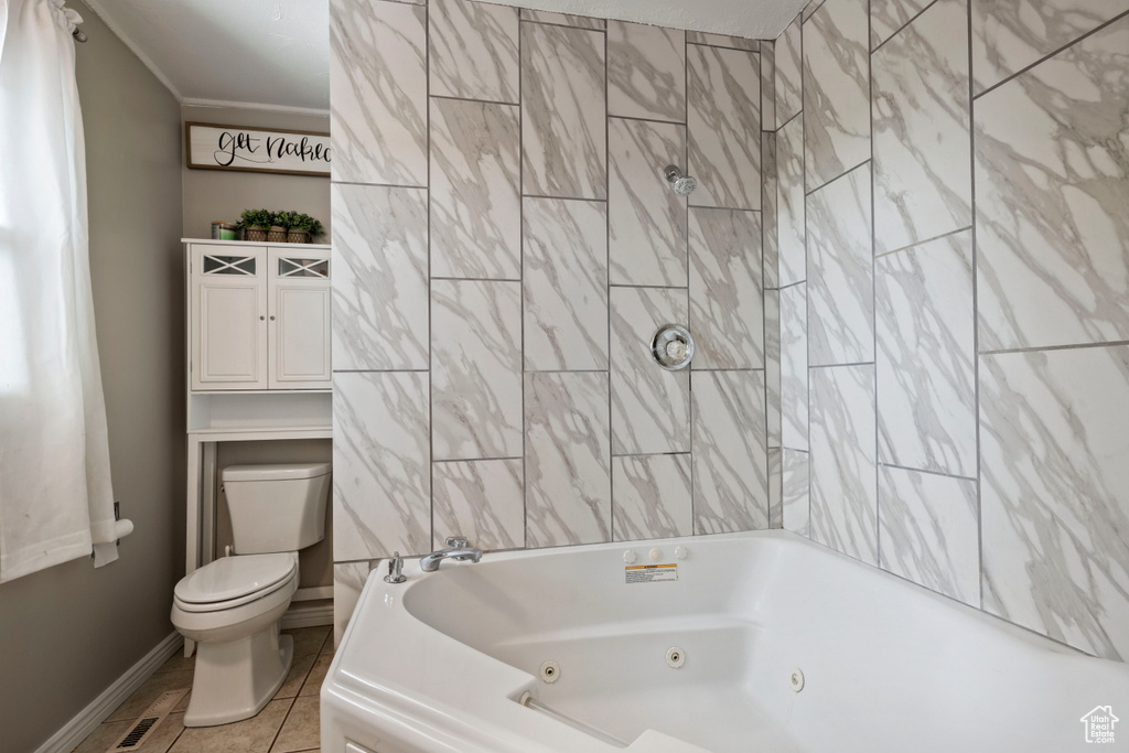 Bathroom with toilet, tile patterned flooring, baseboards, and a combined bath / shower with jetted tub